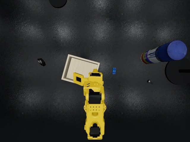 Overhead camera: the arm at rest beside the wooden box, the brick on the bench