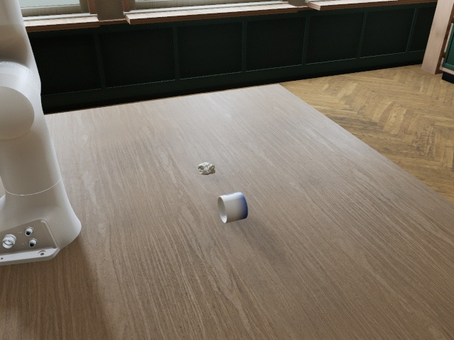 Front camera: the Panda beside a wooden table in a café, the mug on its side and the napkin near it